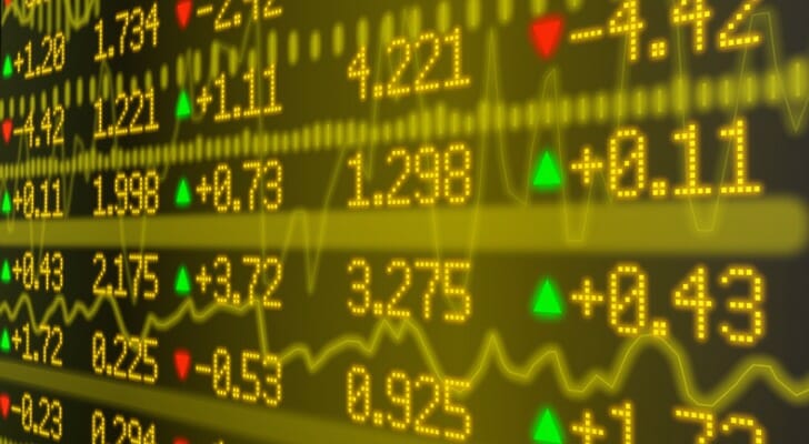 Stock market ticker wall in yellow with various numbers and graphs