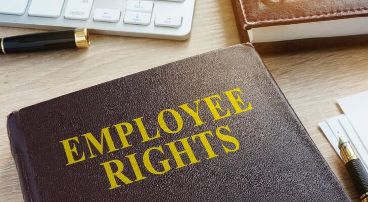 Image shows a brown leather-bound book with "EMPLOYEE RIGHTS" written on the cover in yellow lettering; the book sits on a desk with other office supplies such as a keyboard, notebook and pen. SmartAsset analyzed data on various metrics to conduct its 2020 study on the states with the strongest unions.