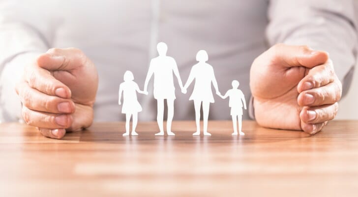 Pair of hands protecting cutout figures of family members