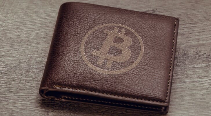Image shows a brown wallet with the Bitcoin symbol stamped on it. If you own Bitcoin, you can use a cold storage wallet to store it offline, which keeps it safe from hacking and other web attacks.