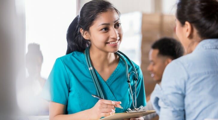 Image shows a nurse practitioner speaking with a patient. SmartAsset analyzed BLS data to identify the most promising jobs for employment and pay.