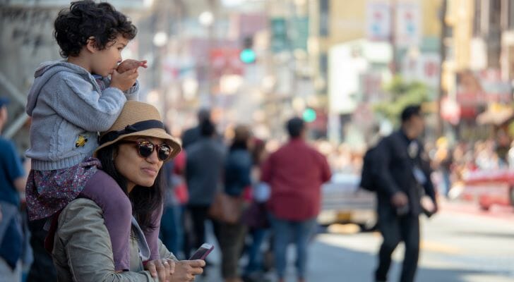 Image shows a parent and child at a parade outside. SmartAsset analyzed various data sources to conduct its study on where Hispanic and Latino Americans fare best economically.