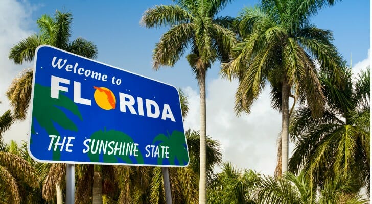 Image shows a sign that reads "Welcome to Florida: The Sunshine State" against a background of palm trees and a sunny blue sky. SmartAsset analyzed IRS data to determine where upper-middle-class people are moving.