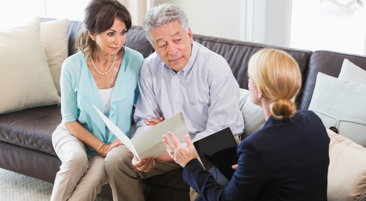 Image shows a couple speaking to a wealth advisor about their long-term financial goals.