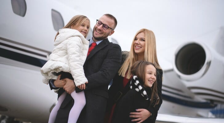 Rich family standing next to a private jet