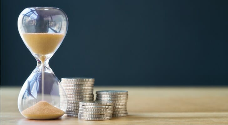 An hourglass sits next to a stack of coins. T. Rowe Price recently published its year-end tips for retirement savers. 
