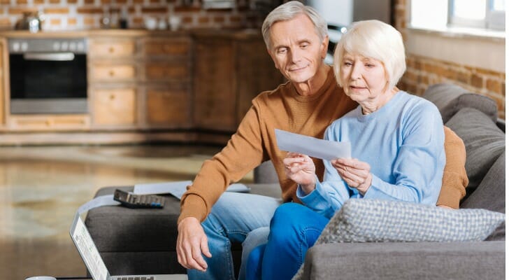 A retired couple looks over a Social Security check. Getting a mortgage with only Social Security benefits is possible, but not having regular income from a job or retirement accounts can make it more challenging.