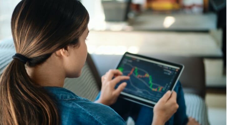 A woman trades cryptocurrencies online while sitting on her couch. Many people view the cryptocurrency landscape as a short-term opportunity, but you can also invest in it for the long term.