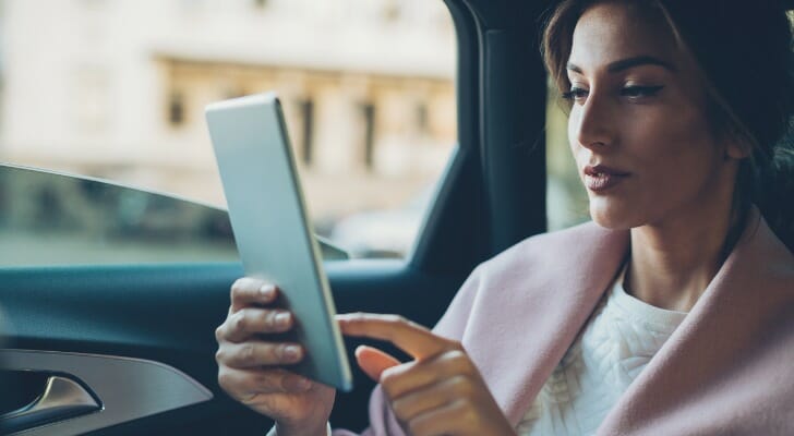 A woman looks over her investment portfolio in her car. High-net-worth individuals can use a number of strategies to minimize taxes, including investing in tax-advantaged investments and accounts.