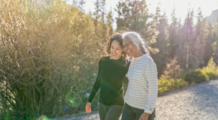This image shows a retiree walking with her daughter. Retirees are staying in defined-contribution plans years into their retirement.