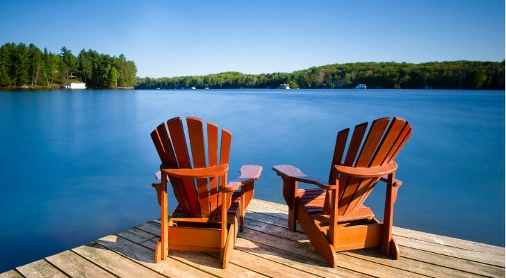 Two Adirondack chairs on a lakeside dock