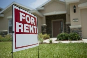 A &quot;For Rent&quot; sign sits in front of a house.