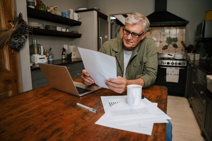 A retiree who does freelance consulting works at his kitchen table. 