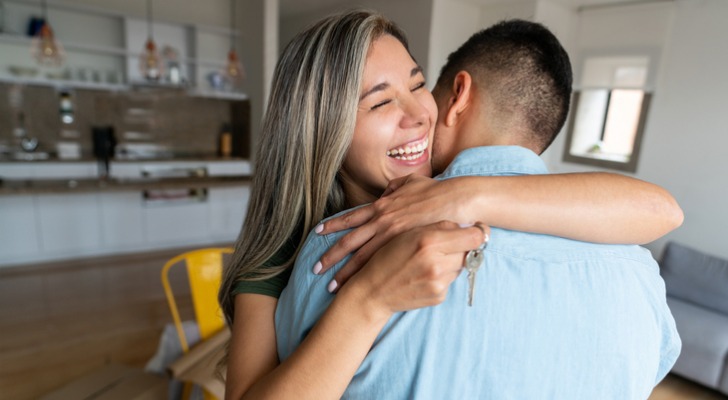 A couple hugs after paying off their mortgage early using mortgage curtailment.