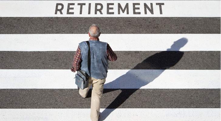 Older man walking on pavement that has "RETIREMENT" painted on it