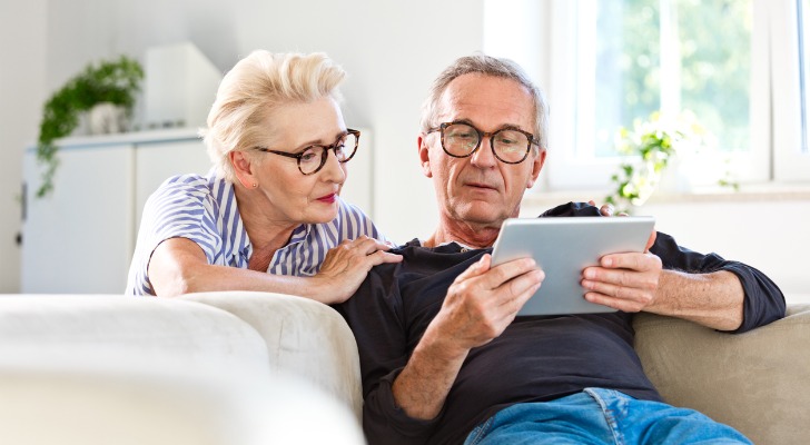 A worried couple looks over their retirement savings on a tablet. 