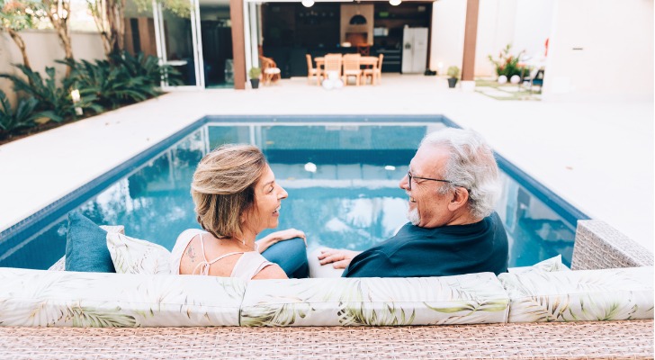 A wealthy retired couple relaxes poolside at their home. 