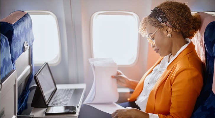 A businesswoman looks over paperwork while on an international flight.