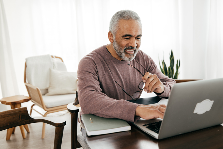 Senior man smiling at the computer while sitting at a table