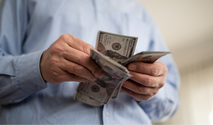 A retiree counts cash he's using to cover living expenses.
