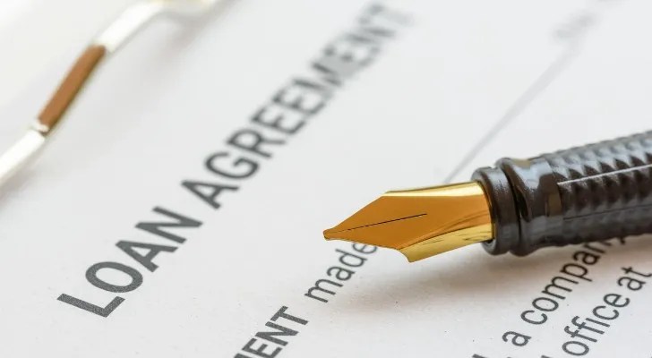 A pen sits on top of a loan agreement that's ready to be signed.