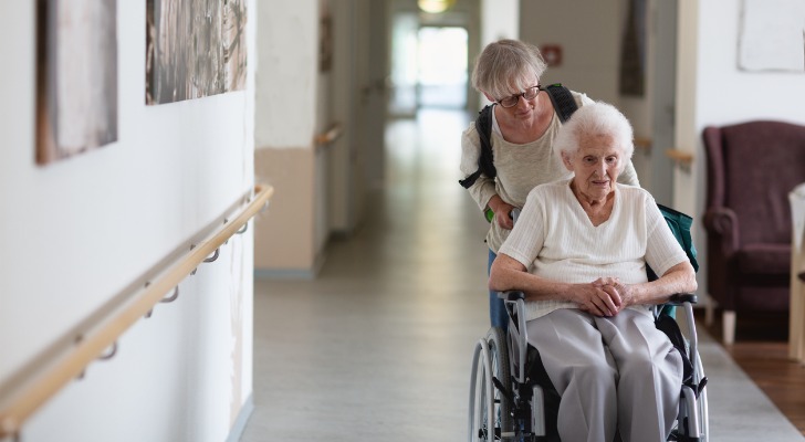 A Medicaid recipient is wheeled through a nursing home. 