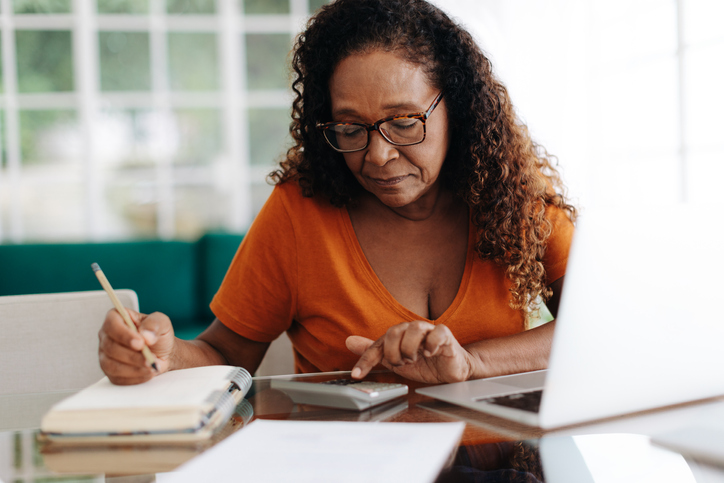 A senior woman calculating how much she will need to save by specific age milestones.