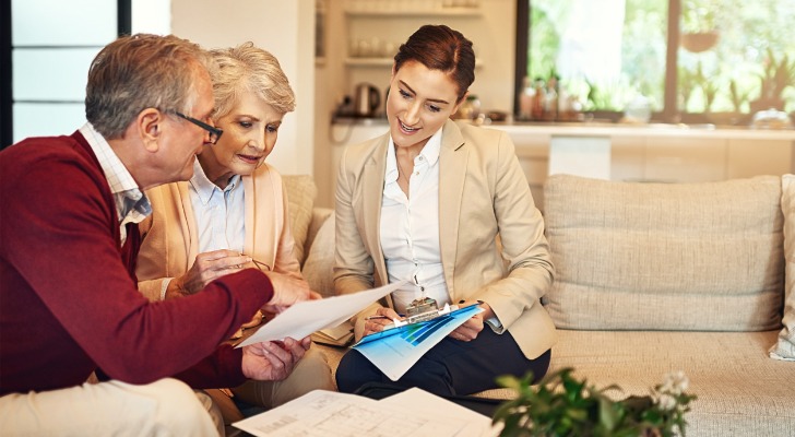 A senior couple comparing the differences between a living trust and a will with a financial advisor.