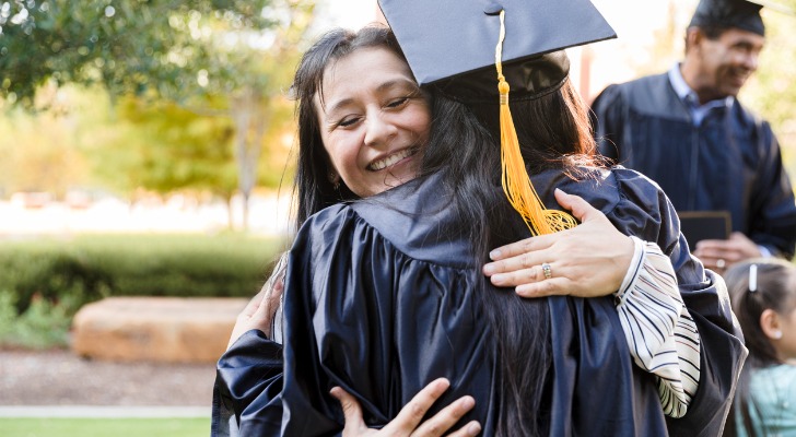 A mom hugs her child after graduating from college.