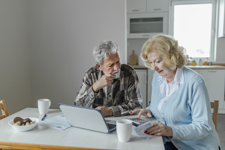 A senior couple calculating how much money they need to pay for retirement expenses.
