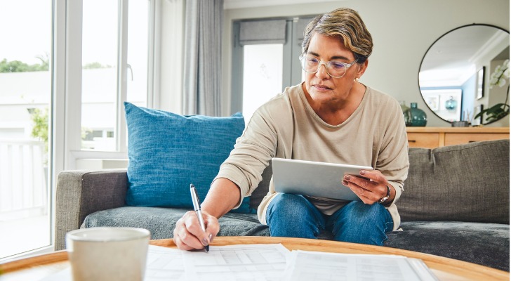 A woman fills out tax forms while reviewing her 401(k) balance and AGI.