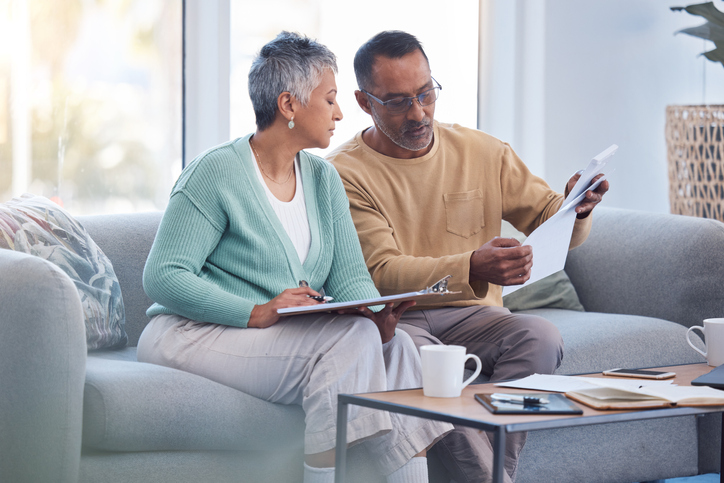 A senior couple reviews the terms of multiple healthcare plans.