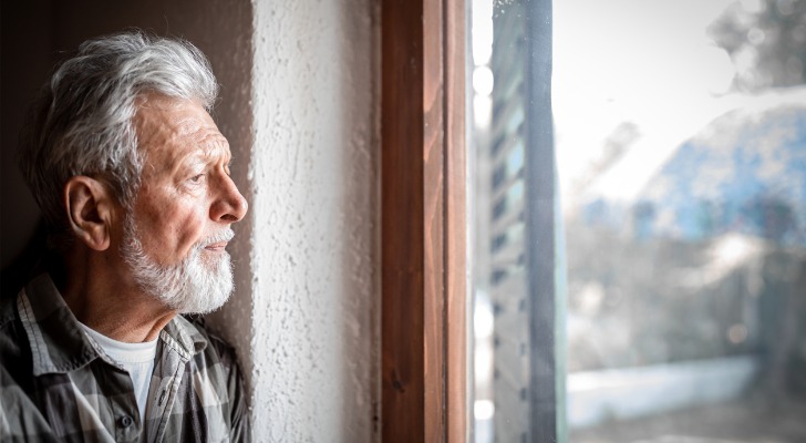 A recent widower has a moment of reflection as he looks out a window. 