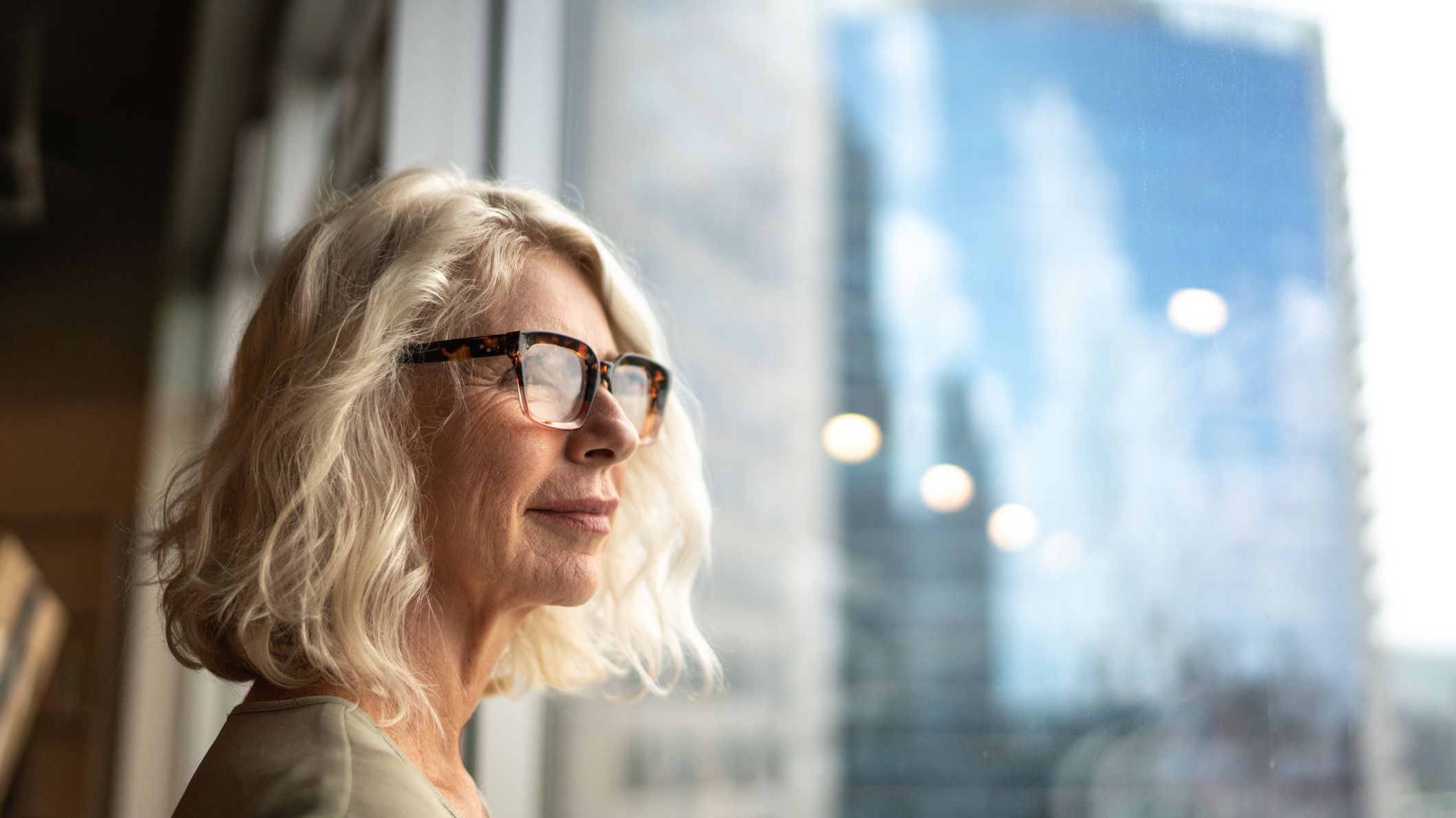 A woman looks out the window of her office as she thinks about her plan for retirement.