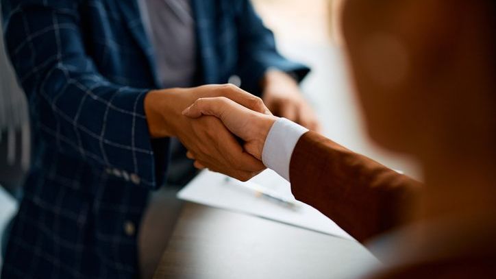 Financial advisors shake hands after a meeting.