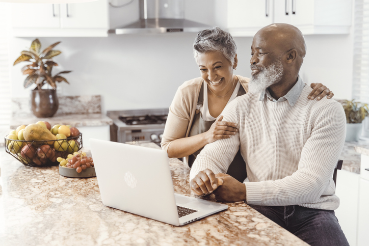 A husband and wife in their early 60s smile as they look over their financial plan for retirement.