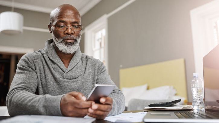 A man who's approaching retirement looks over his 403(b) account balance on his phone.