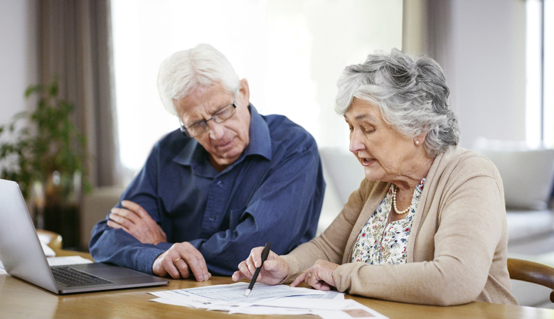 A senior couple looking at a referral from a friend to set up an interview with a financial advisor.