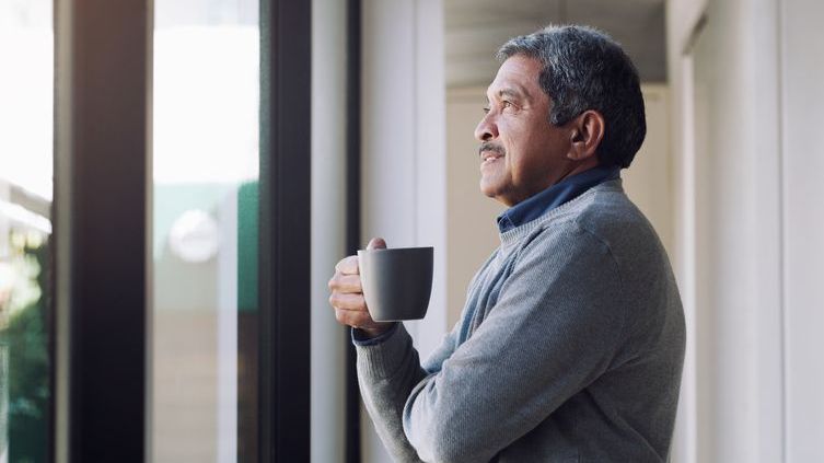 A retirement business owner relaxes with a cup of coffee. 