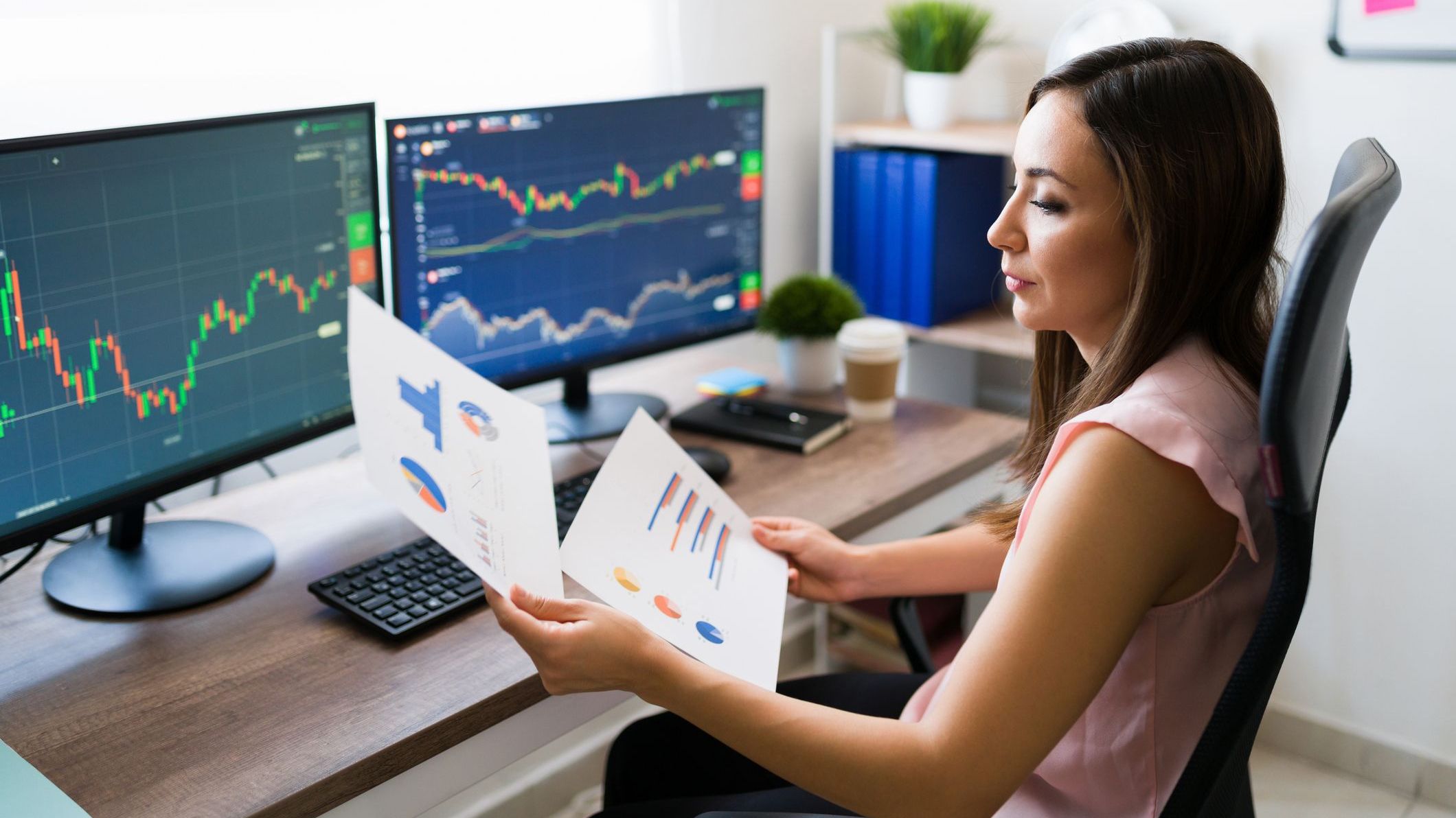 A stockbroker looks over charts and graphs at her desk.