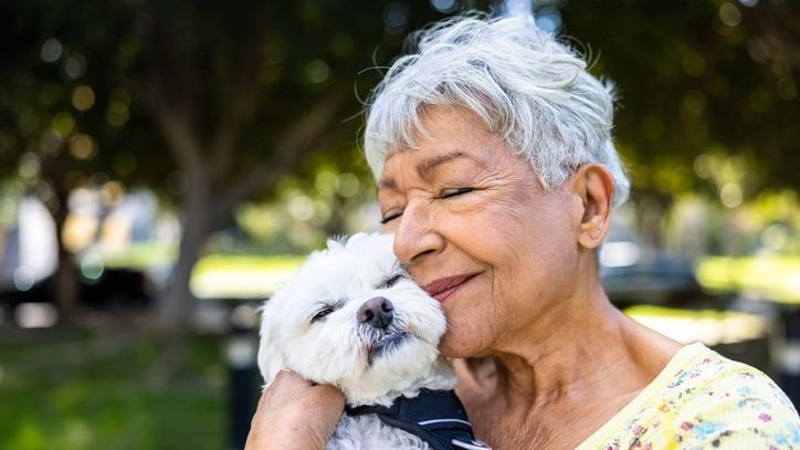 A 75-year-old retiree embraces her dog during an afternoon walk.