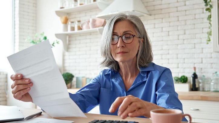 A woman looks over her 401(k) account statement to determine whether she should make catch-up contributions.