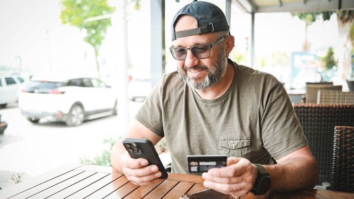 A man uses his cell phone to reload his prepaid card with additional funds.