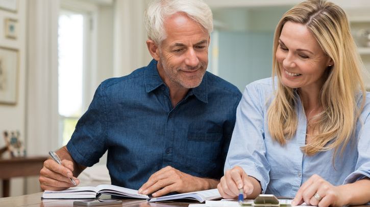 A husband and wife go over their finances to determine whether they can afford to retire at age 62.