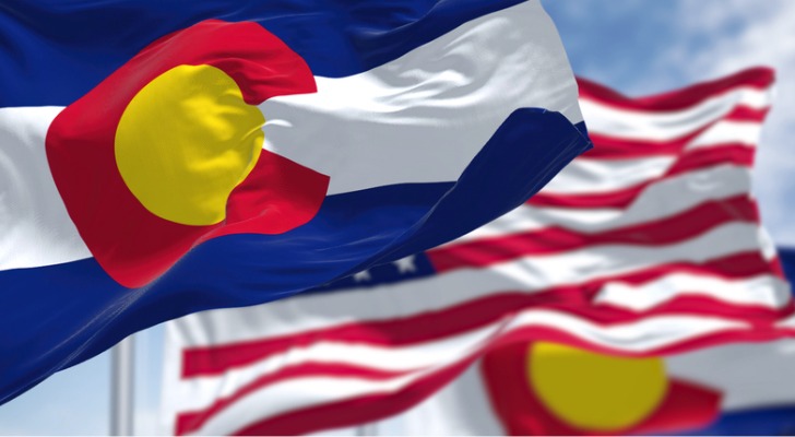 The Colorado state flag waves in the air in front of an American flag. 