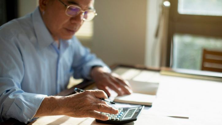 A man works on his retirement budget by adding up his expected expenses will be.