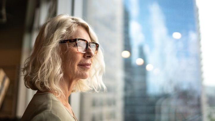 A woman looks out the window of her office and contemplates her retirement plan.