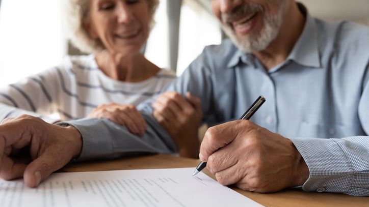 A husband and wife sign estate planning documents. 