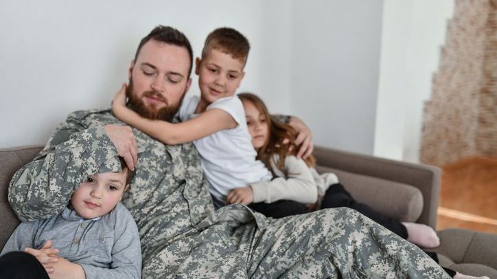 A soldier embraces his three children before deploying for a tour of active duty.