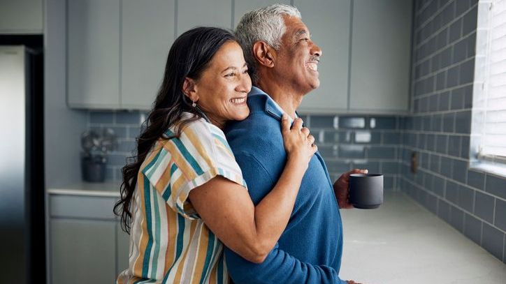A woman hugs her husband while talking about their plan for retirement.